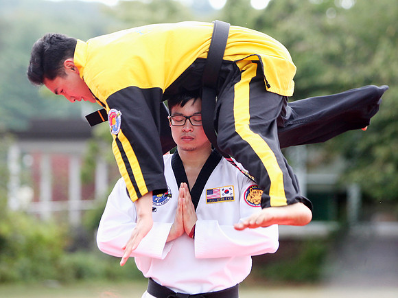 Lawrence Laxina stands still as fellow student from the All Star Taekwondo School, Matthew Reyes jumps over him as part of the performance by the school's students.